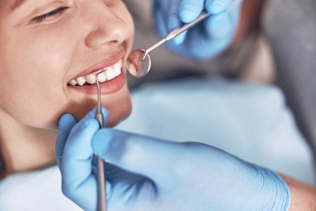 Dental professional cleaning a patient’s teeth with a dental instrument